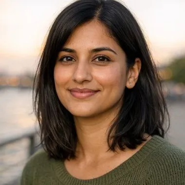 South Asian woman in her late twenties, shoulder-length dark hair, warm expression
